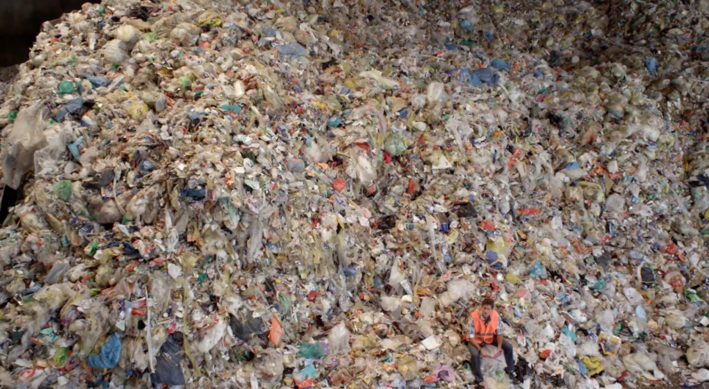 Craig Leeson sitting in a pile of trash.